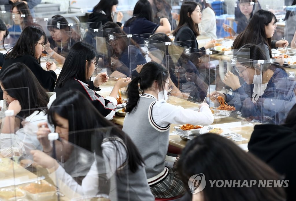 High school seniors at Doan High School eat lunch in a school cafeteria with plastic barriers serving as protection from COVID-19 in Daejeon, 164 kilometers south of Seoul, on May 20, 2020. (Yonhap)