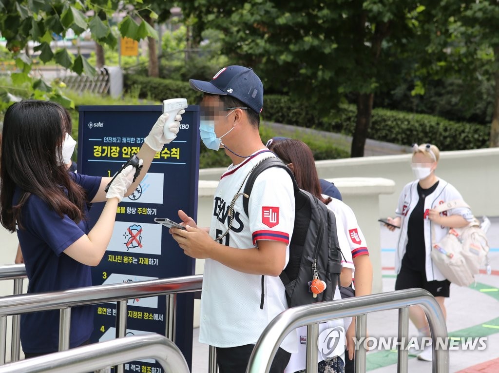 A South Korean baseball fan in a Doosan Bears jersey has his temperature checked before entering Jamsil Baseball Stadium in Seoul for a Korea Baseball Organization regular season game between the Bears and the LG Twins on July 26, 2020. (Yonhap)