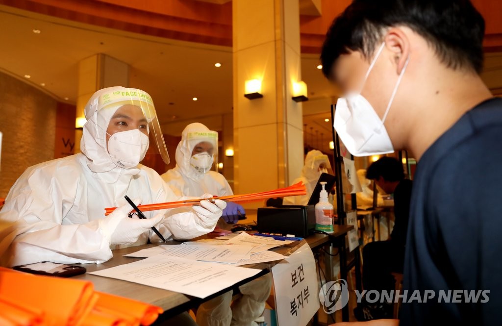 This photo taken by Joint Press Corps on Aug. 5, 2020, shows health workers explaining quarantine policies at a temporary quarantine shelter in Incheon. (Yonhap)