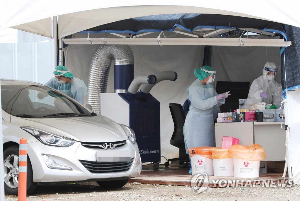 Health workers conduct virus tests at a drive-through COVID-19 screening clinic in Seoul on Aug. 28, 2020. (Yonhap)