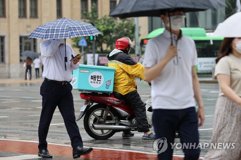 Pedestrians wearing protective masks pass by a delivery motorcycle in central Seoul on Sept. 2, 2020. (Yonhap)