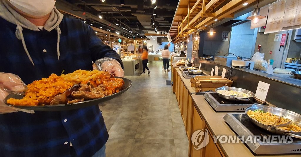 A customer takes a plate of food at a buffet restaurant in Seoul on Oct. 12, 2020. (Yonhap)