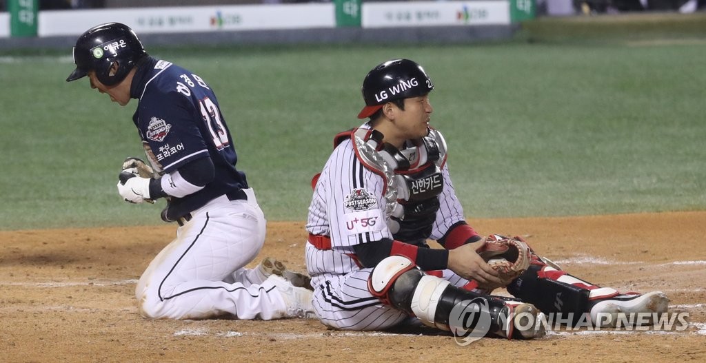 Heo Kyoung-min of the Doosan Bears (L) celebrates after scoring past LG Twins catcher Yoo Kang-nam in the top of the fourth inning of Game 2 of the Korea Baseball Organization first-round postseason series at Jamsil Baseball Stadium in Seoul on Nov. 5, 2020. (Yonhap)