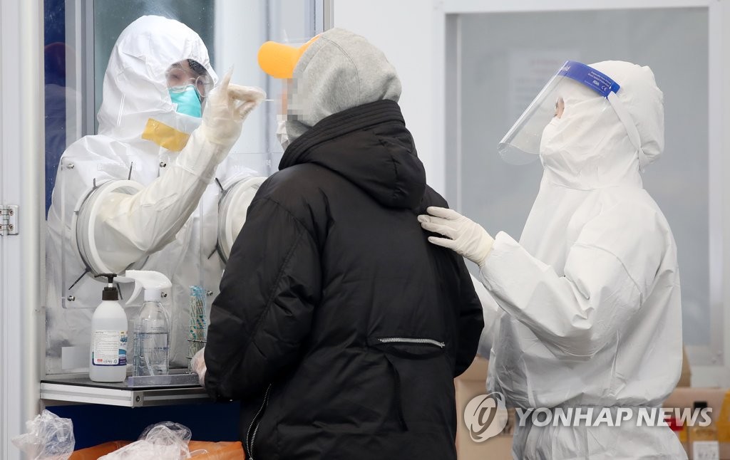 Medical workers collect a specimen from a man for COVID-19 testing at a screening station in southern Seoul on Nov. 26, 2020. (Yonhap) 