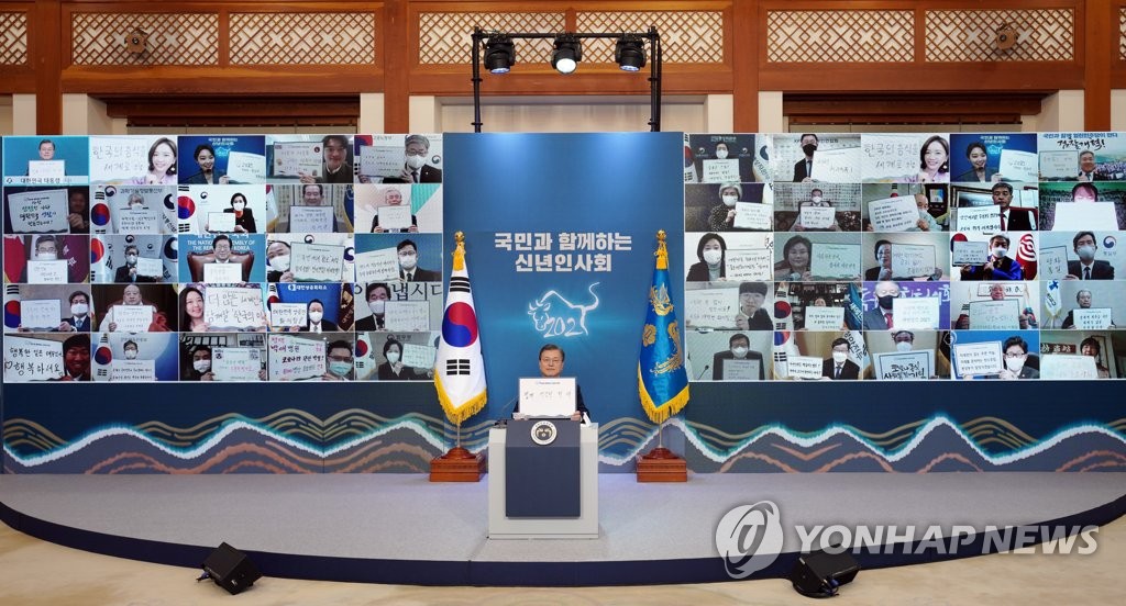 President Moon Jae-in poses for a commemorative photo during a New Year's meeting with business and social leaders held via video links at Cheong Wa Dae in Seoul on Jan. 7, 2021. Moon and other participants are showing papers with their wishes. (Yonhap) 