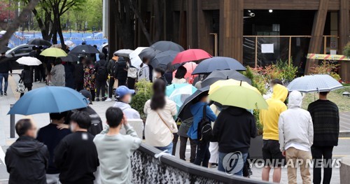 松坡区保健所で傘を差して新型コロナウイルスの検査を待つ市民＝１２日、ソウル（聯合ニュース）
