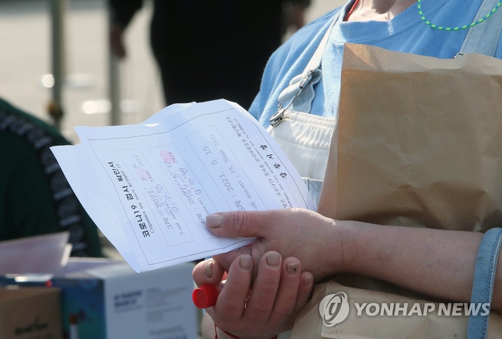 This May. 12, 2021, file photo shows a migrant worker in holding a COVID-19 test document at a virus test center in Gangneung, about 240 kilometers east of Seoul. (Yonhap)
