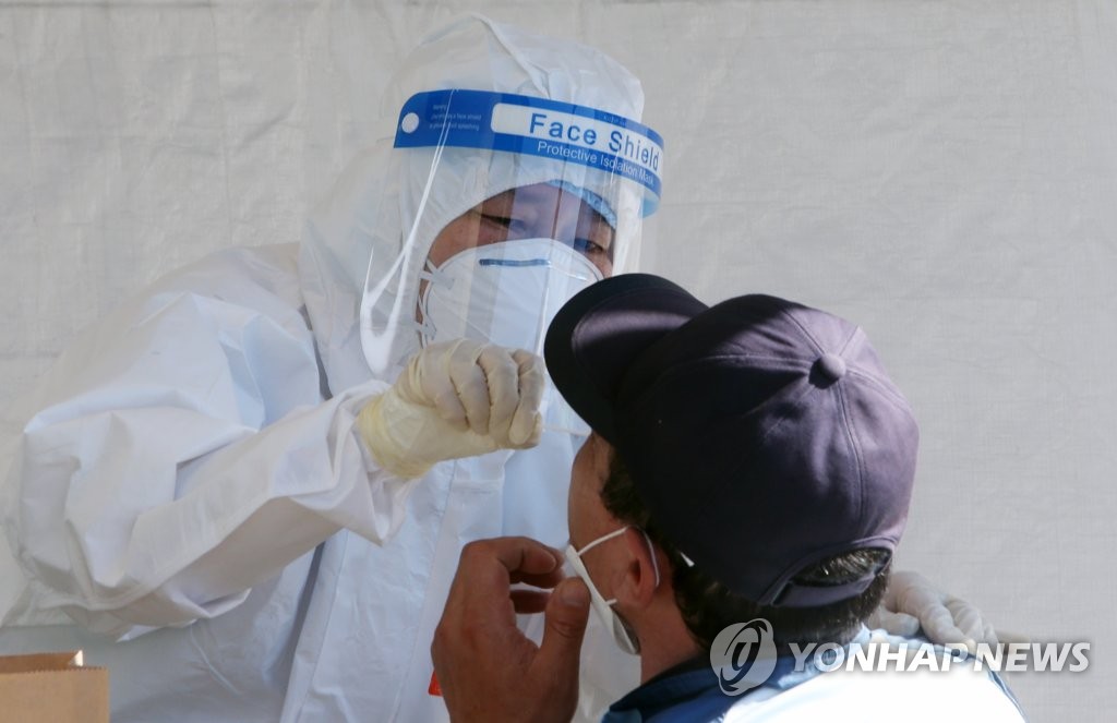 This May 18, 2021, file photo shows a medical worker taking a sample from a foreign worker at a COVID-19 testing station in Gangneung, 240 kilometers east of Seoul. (Yonhap)