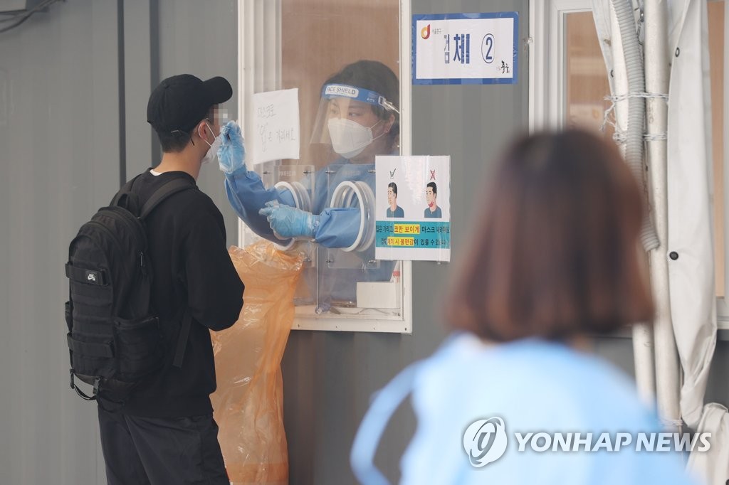 A medical worker collects samples from a person for a COVID-19 test at a temporary test center near Seoul Station in the capital on the Buddha's Birthday holiday on May 19, 2020. (Yonhap)