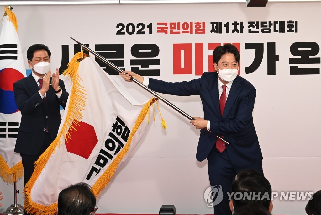 Lee Jun-seok, 36, waves the flag of the main opposition People Power Party after being elected as its chairman at the party's national convention in Seoul on June 11, 2021. He became the youngest-ever leader in the history of the country's main political parties. (Yonhap)