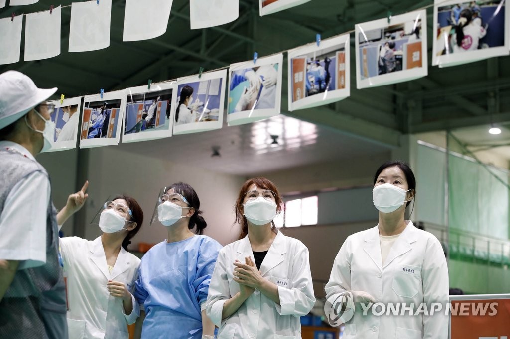 Des employés du centre de vaccination de l'arrondissement de Buk à la ville de Gwangju regardent des photos prises lors de vaccinations, 123 jours après le début de la campagne vaccinale, le lundi 28 juin 2021. (Photo fournie par la mairie de Buk à Gwangju. Revente et archivage interdits) 