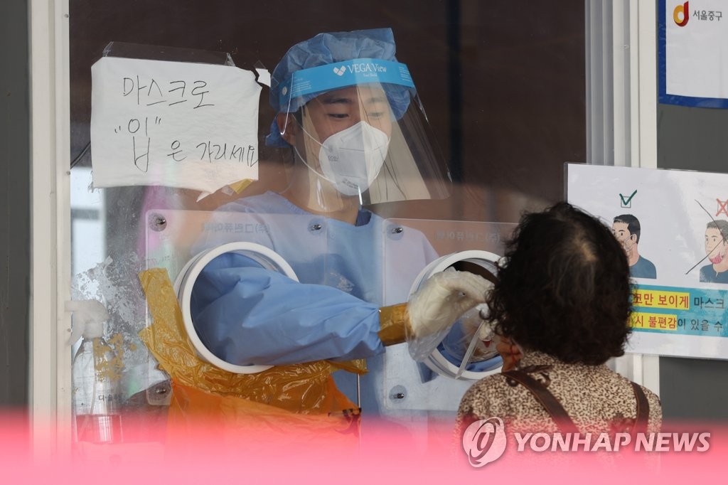 A medical staff member collects specimens from a person for COVID-19 testing at a screening station in Seoul on Aug. 11, 2021. (Yonhap)