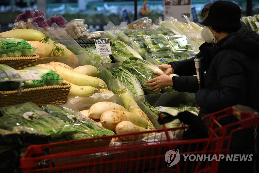 This photo, taken Dec. 13, 2021, shows a shopper selecting produce at a discount store in Seoul amid rising inflation. (Yonhap)
