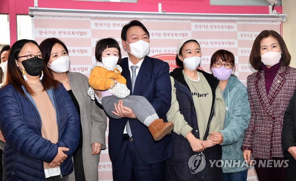 Yoon Suk-yeol (C), the presidential nominee of the main opposition People Power Party, poses with a child and members of a single parents association in Seoul on Dec. 15, 2021. (Pool photo) (Yonhap)
