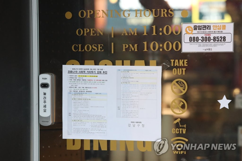 A Seoul restaurant puts COVID-19 social distancing guidelines on its front door on Dec. 30, 2021. (Yonhap)