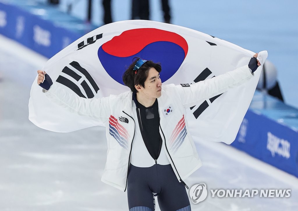 Le patineur de vitesse de l'équipe sud-coréenne, Cha Min-kyu, fait le tour de la patinoire en brandissant le drapeau national de la Corée du Sud après avoir remporté la médaille d'argent à l'épreuve du 500m hommes aux Jeux olympiques d'hiver de Pékin 2022, à l'Anneau national de patinage de vitesse à Pékin, le samedi 12 février 2022.