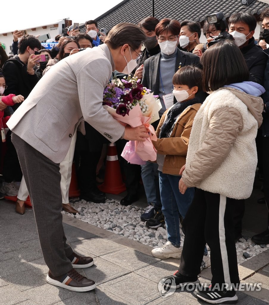 Lee Jae-myung, the presidential candidate of the ruling Democratic Party, receives a bouquet from a boy during a campaign stop in Gyeongju, North Gyeongsang Province, on Feb. 28, 2022, ahead of the March 9 election. (Yonhap)
