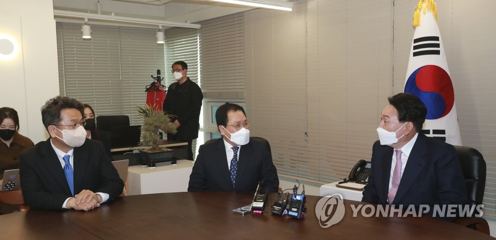 President-elect Yoon Suk-yeol (R) talks with presidential chief of staff You Young-min (C) and Lee Cheol-hee, chief presidential secretary for political affairs, after receiving a congratulatory pot of orchids from President Moon Jae-in at the People Power Party's headquarters in Seoul on March 10, 2022. (Pool photo) (Yonhap)