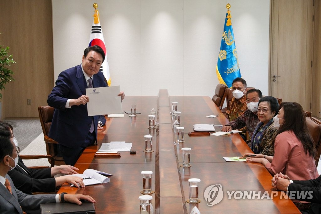 South Korean President Yoon Suk-yeol (L) receives a letter from former Indonesian President Megawati Sukarnoputri (2nd from R), also leader of the ruling Indonesian Democratic Party of Struggle, during their meeting at the presidential office in Seoul's Yongsan Ward on May 11, 2022. (Yonhap)