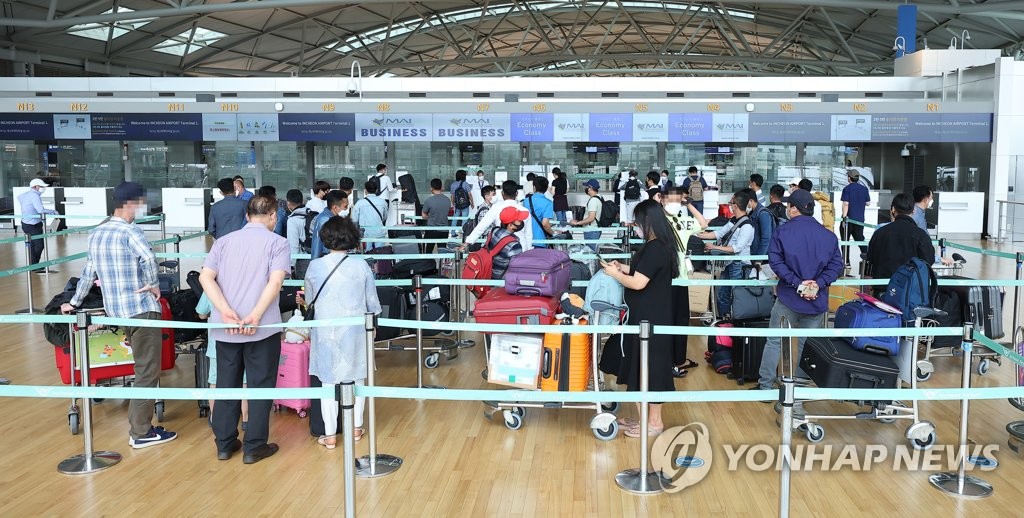 Travelers wait in line at Incheon International Airport in Incheon, west of Seoul, on May 13, 2022. South Korea has decided to ease requirements to enter the country amid a downward trend in COVID-19 cases, a move that could boost convenience for inbound travelers. (Yonhap)
