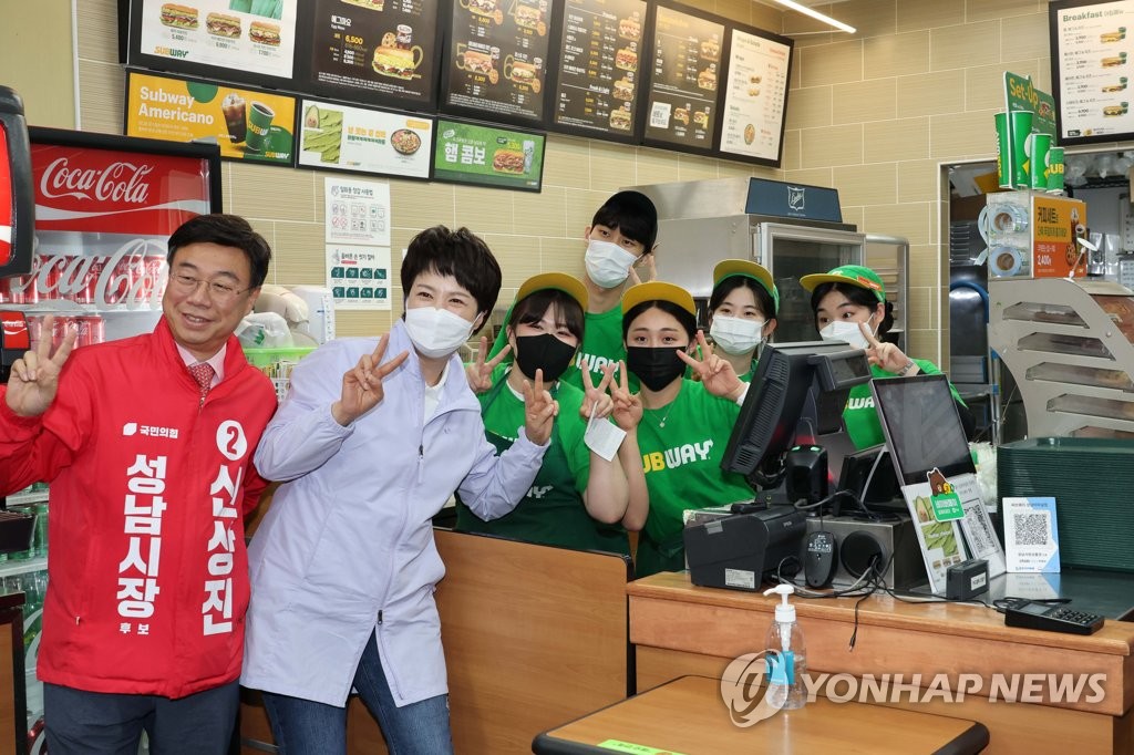 샌드위치 가게 직원들과 기념촬영하는 김은혜와 신상진