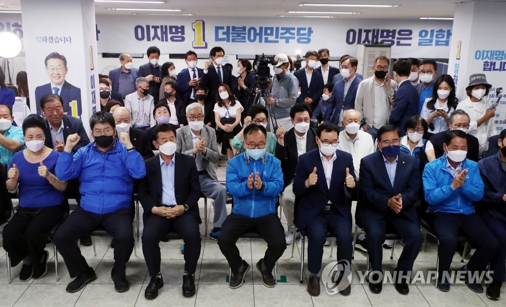 Les partisans de l'ancien candidat présidentiel Lee Jae-myung affilié à la principale formation d'opposition, le Parti démocrate (PD), célèbrent sa victoire au bureau de campagne de Lee à Incheon, à l'ouest de Séoul, le 1er juin 2022, alors qu'ils regardent la couverture télévisée d'un sondage à la sortie des urnes montrant que Lee devrait remporter l'élection parlementaire partielle dans la circonscription de Gyeyang-B de la ville contre Yoon Hyung-sun du Parti du pouvoir du peuple (PPP) au pouvoir.