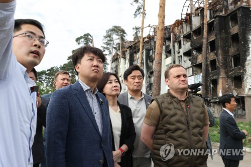 In this photo provided by the People Power Party (PPP) on June 7, 2022, PPP Chairman Lee Jun-seok (2nd from L) and other PPP lawmakers are briefed on damage in Irpin, Ukraine. (PHOTO NOT FOR SALE) (Yonhap)