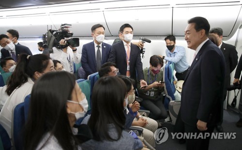 Yoon greets reporters aboard plane