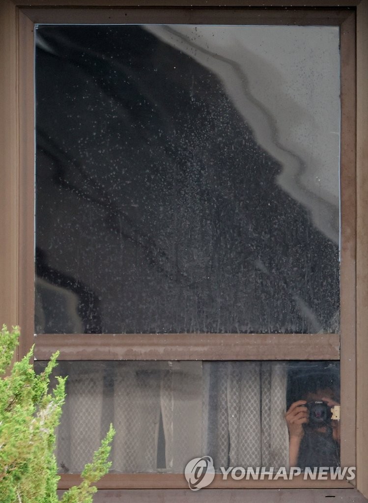 A North Korean official at the Panmungak building, located on the northern side of the truce village of Panmunjom, looks out through the window with a camera facing the South Korean side on July 19, 2022, as tours to the area resumed on July 12. (Yonhap)