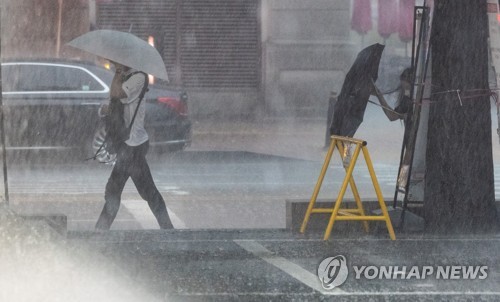 大雨の中を帰宅する人たち＝８日、ソウル（聯合ニュース）