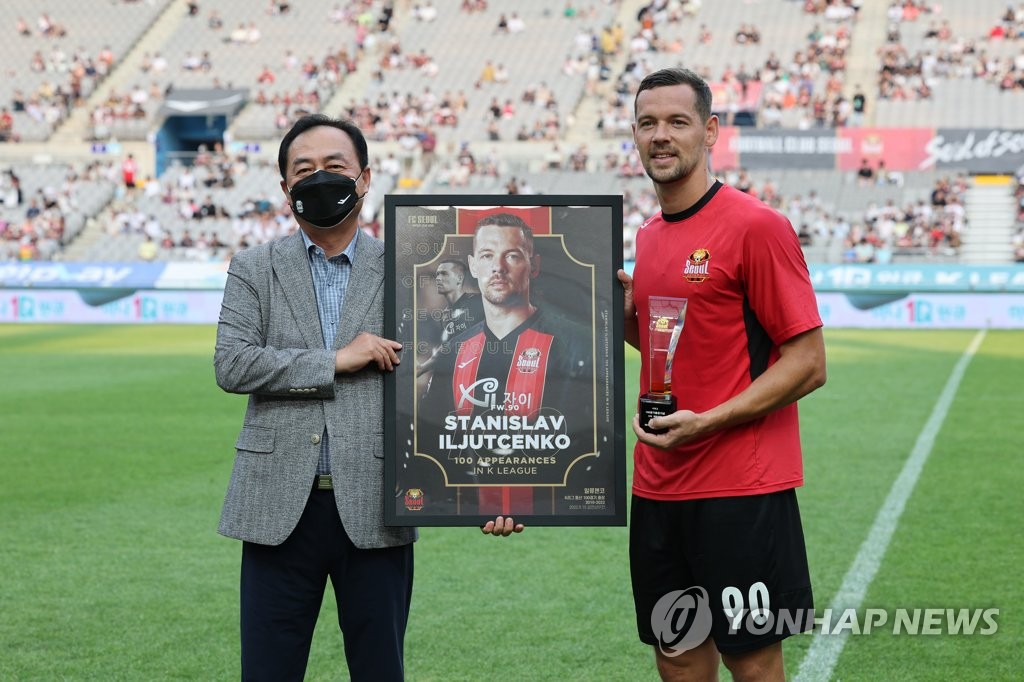 Stanislav Iljutcenko of FC Seoul (R) poses with the plaque celebrating his 100th match in the K League 1 before a match against Seongnam FC at Seoul World Cup Stadium in Seoul on Aug. 21, 2022. (Yonhap)