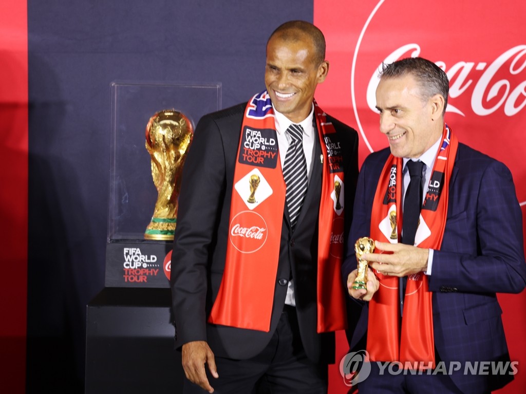 Former Brazil football star Rivaldo (L) and South Korean men's national football head coach Paulo Bento pose next to the FIFA World Cup Trophy during a media showcase in Seoul on Aug. 24, 2022. (Yonhap)