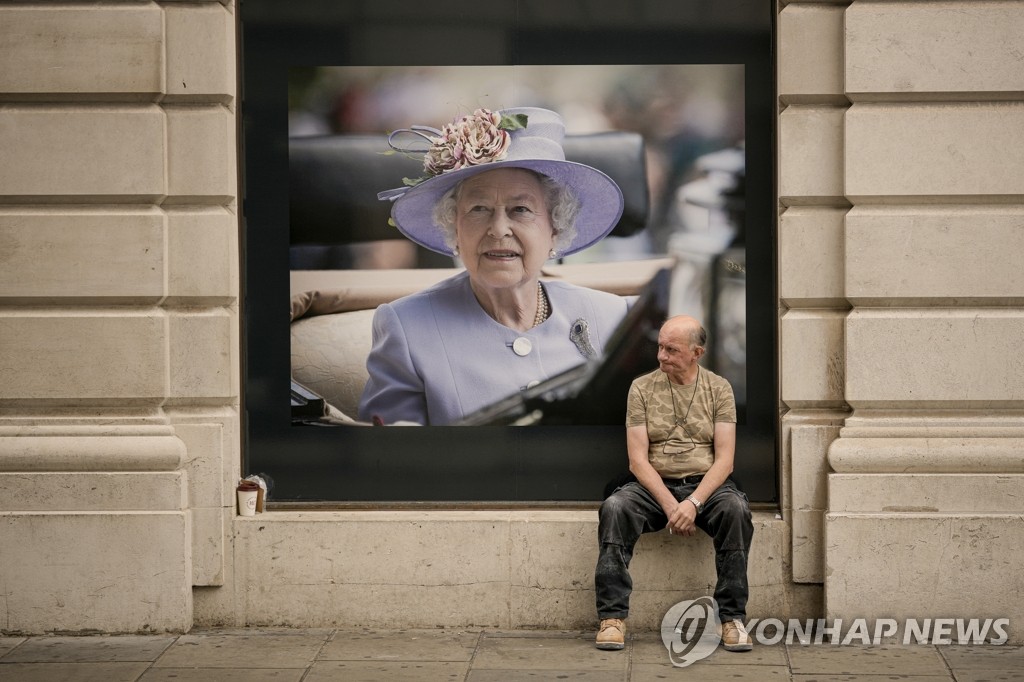 엘리자베스 2세 여왕 초상화 앞에 앉아 있는 영국 시민