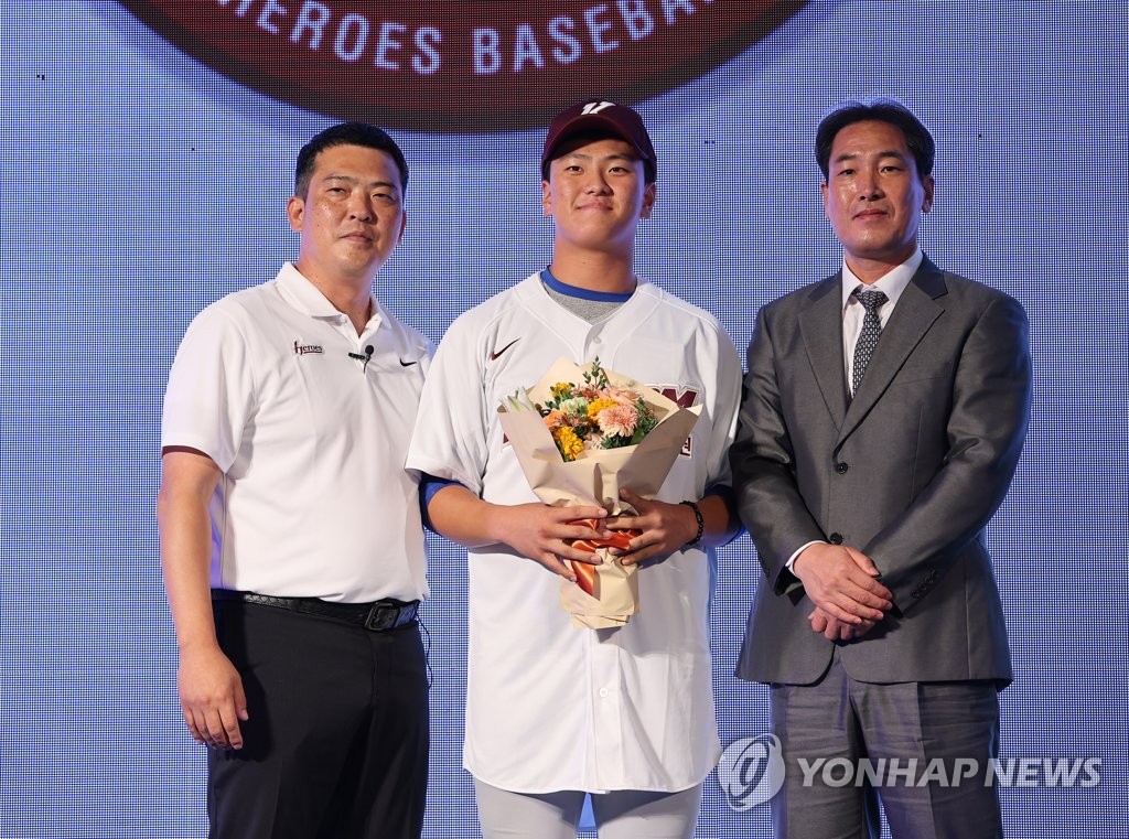 Wonju High School pitcher-catcher Kim Geon-hee (C) poses with Lee Sang-won (L), head of scouting for the Kiwoom Heroes, and Ko Hyung-wook (R), general manager of the Heroes, after being selected sixth overall by the club during the annual Korea Baseball Organization draft at Westin Josun Hotel in Seoul on Sept. 15, 2022. (Yonhap)