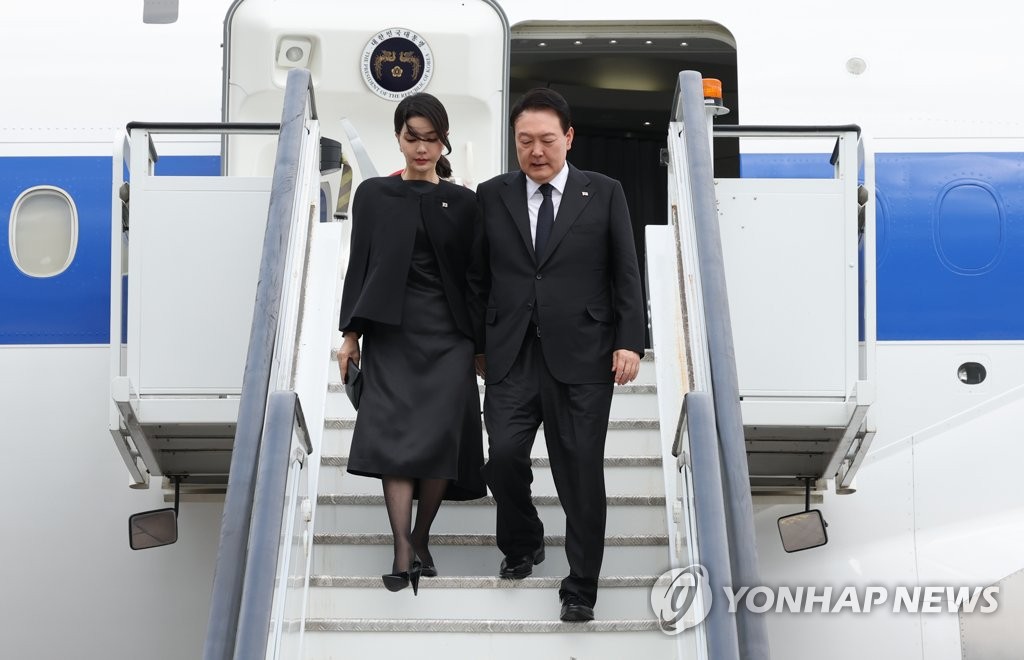 President Yoon Suk-yeol (R) and first lady Kim Keon-hee disembark from the presidential plane after arriving at London Stansted Airport on Sept. 18, 2022. (Yonhap)