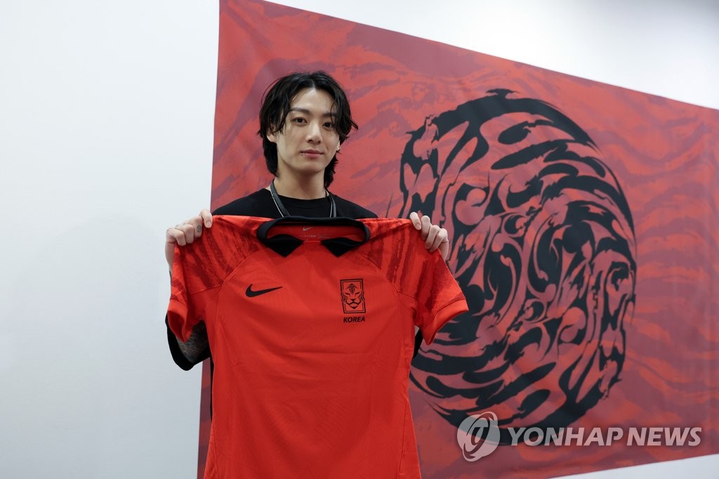 BTS member Jungkook poses with the uniform for the South Korean men's national football team for the 2022 FIFA World Cup, during his visit with the players at Al Egla Training Site in Doha on Nov. 19, 2022, in this photo provided by the Korea Football Association. (PHOTO NOT FOR SALE) (Yonhap)