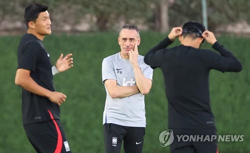 South Korea head coach Paulo Bento (C) watches his players Kim Min-jae (L) and Son Heung-min during a training session for the FIFA World Cup at Al Egla Training Site in Doha on Nov. 22, 2022. (Yonhap)