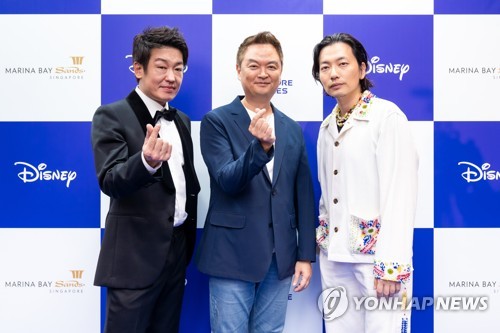 Kang Yoon-sung (C), director of new Korean drama series "Big Bet," and actors Huh Sung-tae (L) and Lee Dong-hwi (R) pose for a photo during a "blue carpet" event for Disney Content Showcase held at Marina Bay Sands in Singapore on Nov. 30, 2022, in this photo provided by Disney. (PHOTO NOT FOR SALE) (Yonhap)