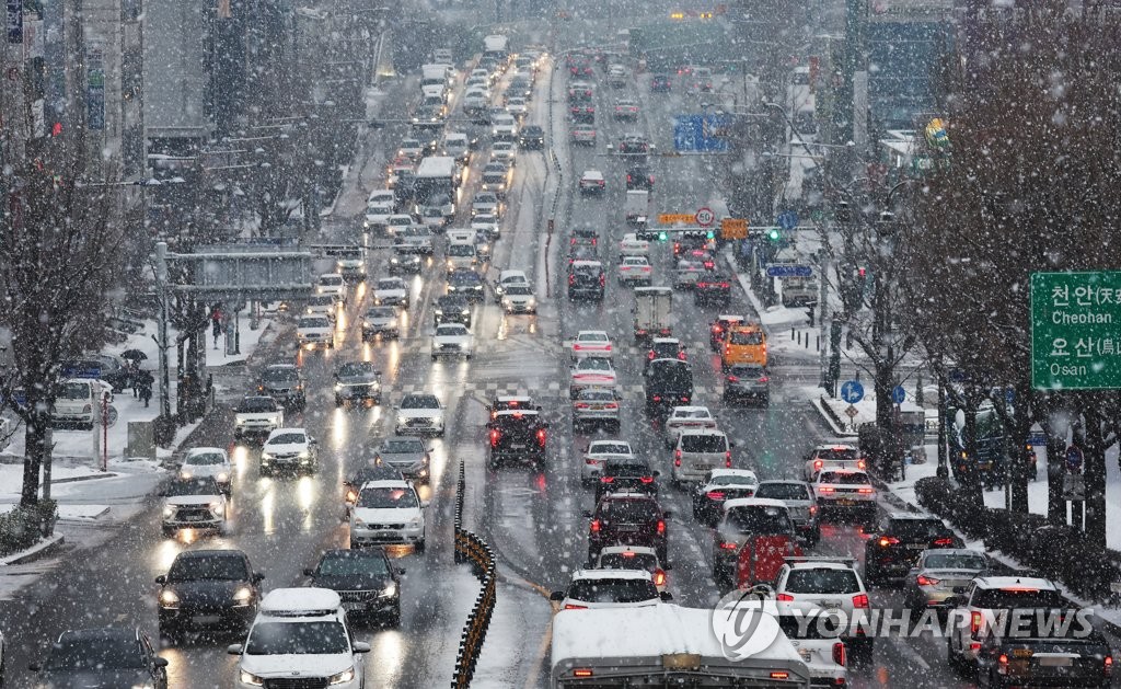 This photo, taken Dec. 21, 2022, shows cars moving slowly on a road in Suwon, south of Seoul, with a heavy snow advisory issued. (Yonhap)