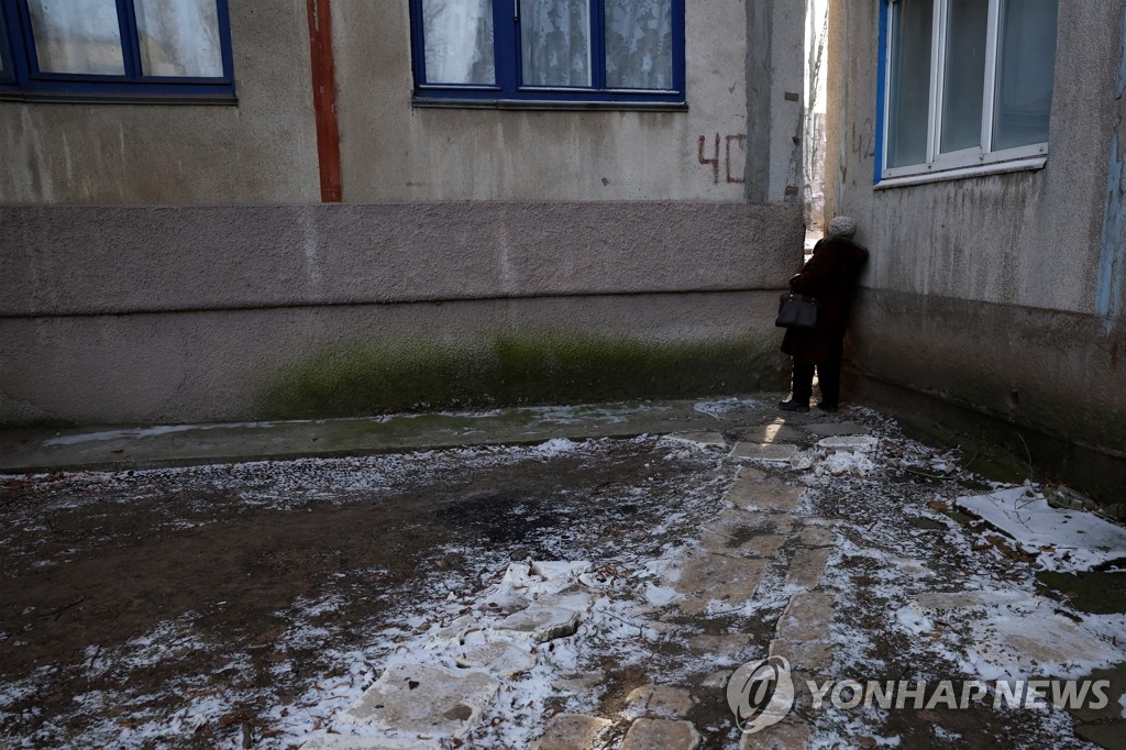 러시아군 포격 동안 건물 사이로 상황 살펴보는 우크라 여성