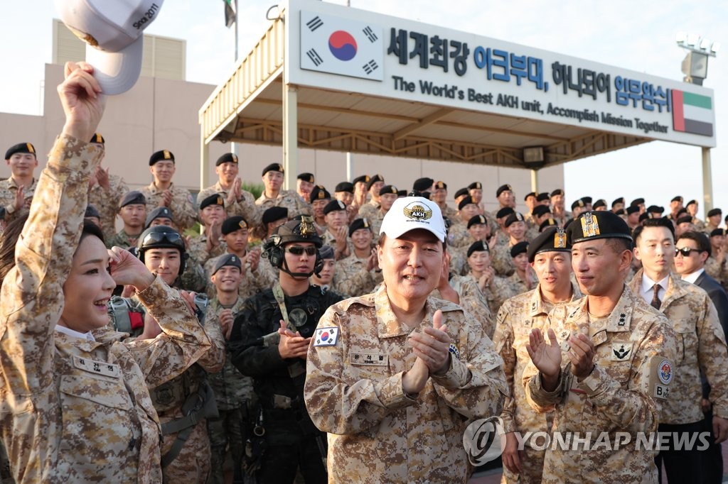 El presidente surcoreano, Yoon Suk Yeol (centro, con gorra blanca), aplaude, el 15 de enero de 2023 (hora local), mientras se reúne, junto con la primera dama, Kim Keon-hee (izda.), con las tropas de la unidad Akh, un contingente militar surcoreano en los EAU.