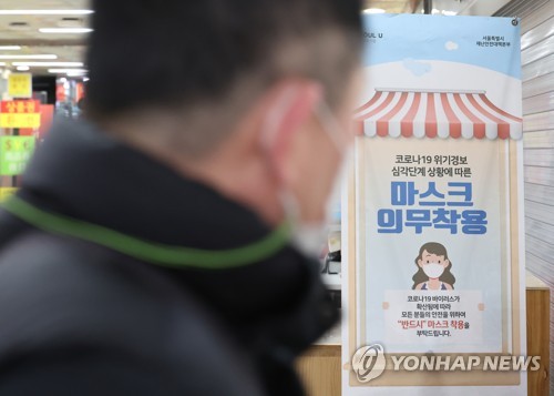 A man walks past a sign asking visitors to wear masks at an indoor shopping mall in Seoul on Jan. 18, 2023. (Yonhap)
