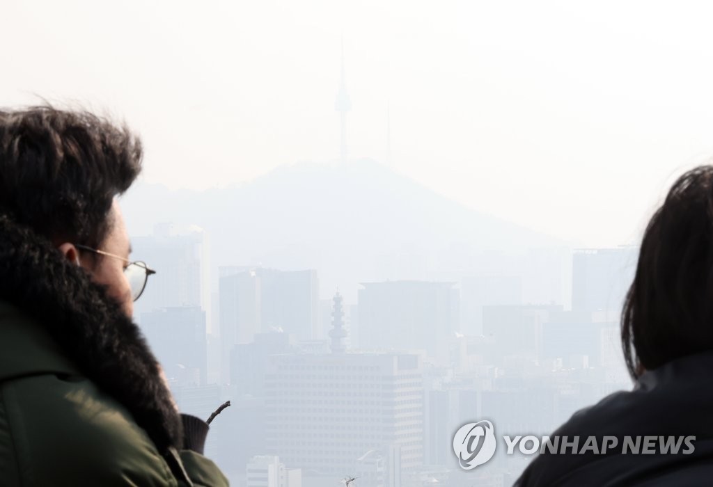 Des promeneurs regardent le dimanche 5 février 2023 le centre de Séoul depuis le mont Inwang alors que la vue est opaque à cause d'un niveau élevé de particules fines.