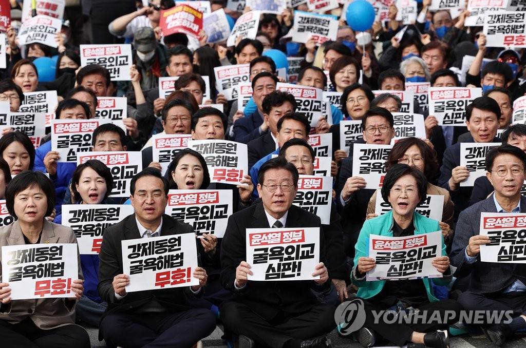 Opposition leader Lee Jae-myung (C) and other participants hold signs protesting against the government's compensation plan for victims of Japan's wartime forced labor in a rally held in central Seoul on March 11, 2023. (Yonhap)