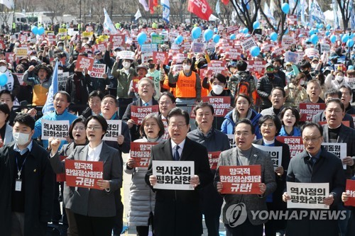 La foto muestra a Lee Jae-myung (centro, frente), líder del principal partido de la oposición, el Partido Democrático, y otros participantes gritando consignas durante una manifestación, celebrada, el 18 de marzo de 2023, en Seúl, para denunciar la cumbre, del 16 de marzo, entre el presidente surcoreano, Yoon Suk Yeol, y el primer ministro japonés, Fumio Kishida.