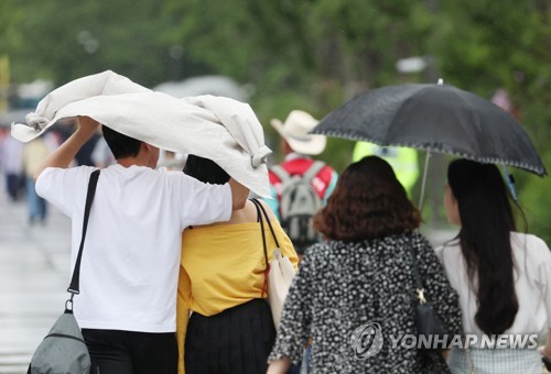 6일 광화문광장을 지나는 시민들이 비를 옷으로 막으며 걸어가고 있다. [연합뉴스 자료사진]