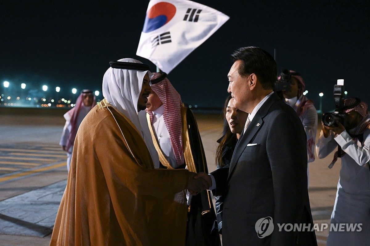 El presidente surcoreano, Yoon Suk Yeol (dcha.), saluda con un apretón de manos a un funcionario saudí, el 21 de octubre de 2023 (hora local), a su llegada al Aeropuerto Internacional Rey Khalid, en Riad, Arabia Saudita. (Foto del cuerpo de prensa. Prohibida su reventa y archivo)
