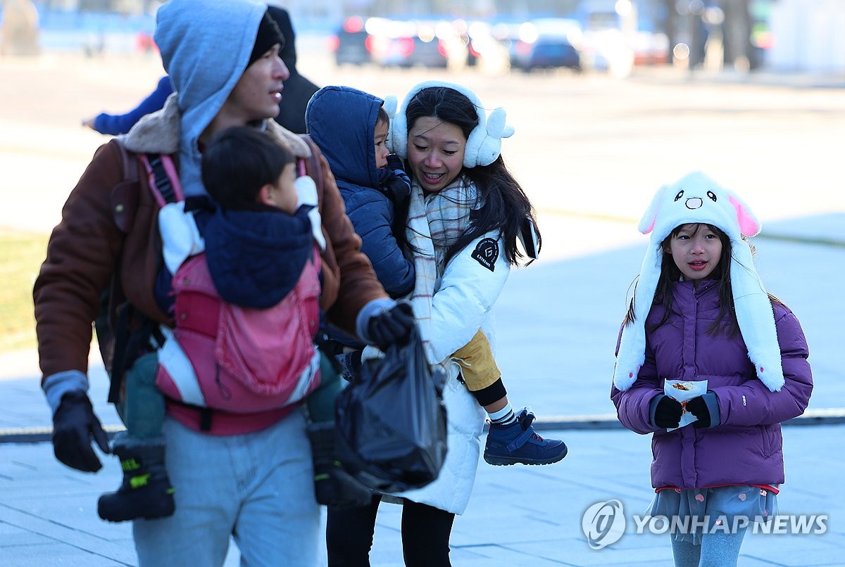 Turistas vestidos con gruesas ropas de invierno dan un paseo cerca del Palacio Gyeongbok en Seúl, mientras Corea del Sur se ve afectada por el clima más frío de la temporada, el 17 de diciembre de 2023. (Yonhap)