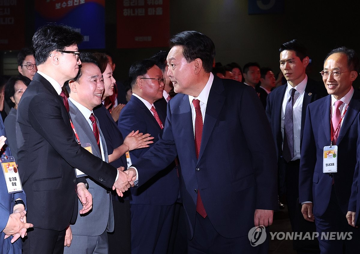 El presidente Yoon Suk Yeol (segundo desde la izq.) estrecha la mano de Han Dong-hoon (izq.), candidato a líder del gobernante Partido del Poder Popular, durante una convención nacional celebrada en KINTEX en Goyang, al norte de Seúl, el 23 de julio de 2024. (Foto de grupo) (Yonhap)