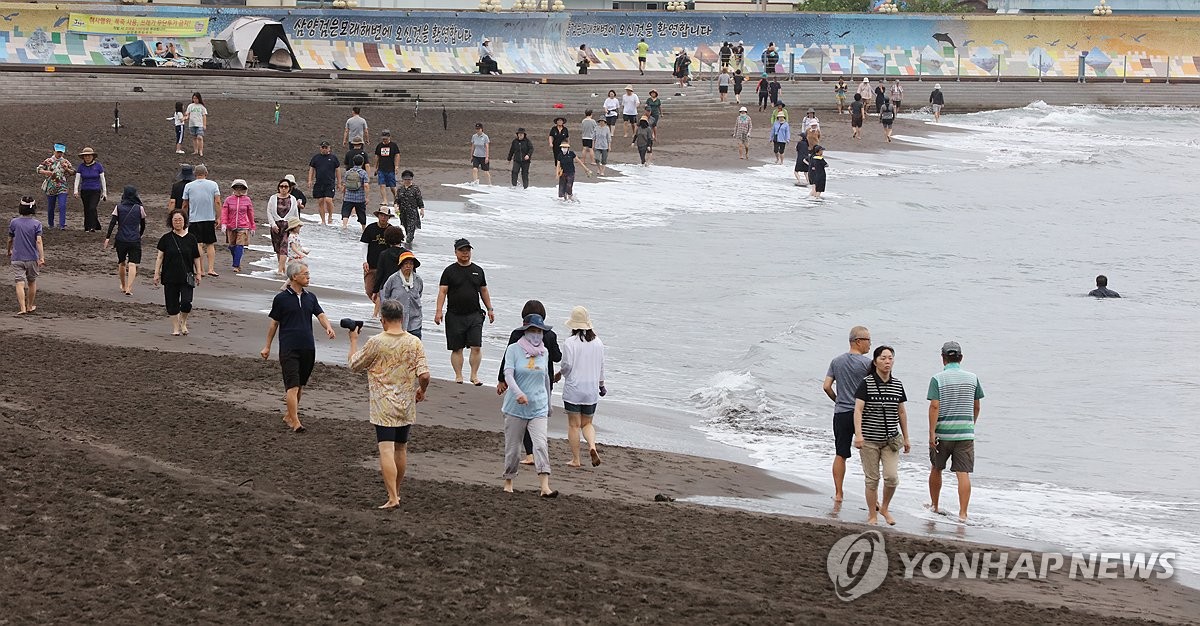 이른 아침 제주 삼양해수욕장에서 맨발 걷기 하는 사람들